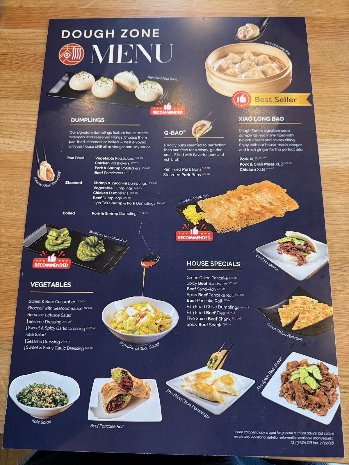 The first page of the Dough Zone menu, showing dumplings, Q-Bao steamed pork buns, xiao long bao soup dumplings, and house specials like beef sandwiches and green onion pancake